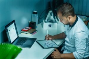 Freelance designer creating digital artwork on a tablet while offering Most Profitable Fiverr Services like graphic design and illustration from a professional home office.
